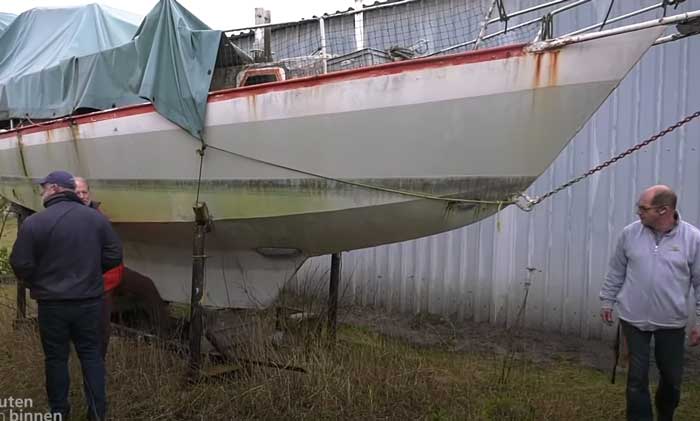 Drei Männer begutachten ein Schrottboot